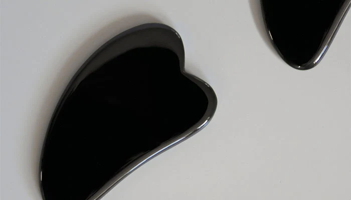 A gua sha stone and serum bottle for a relaxing facial massage routine.