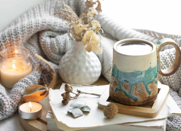 A cozy winter scene with a steaming mug, cinnamon sticks, gingerbread cookies, and a candle, perfect for a 30-Day Winter Self-Care Challenge, set against a snowy backdrop