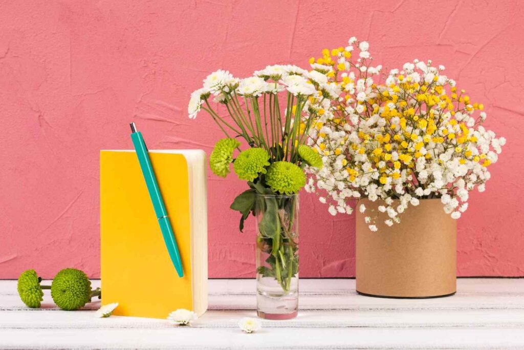 Bright aesthetic workspace with watercolor paint palettes, brushes, and a small vase of spring flowers for a creative mental reset.