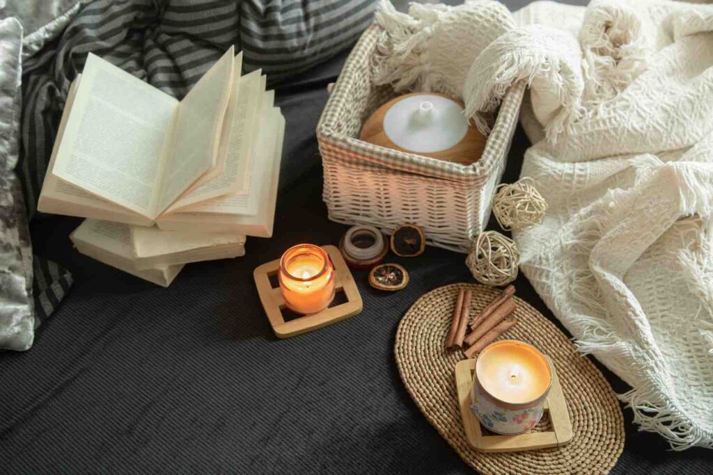 A peaceful minimalist reading corner featuring a stack of linen-covered books and a small lit candle on a side table.