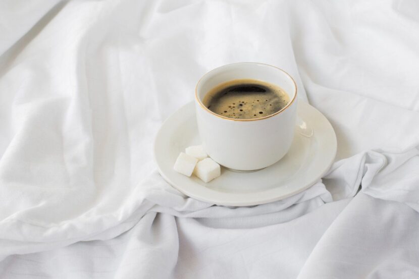 A bright, high-quality photo of a steaming coffee mug next to an open planner on a white desk with soft morning sunlight, perfect for Tuesday morning inspiration.