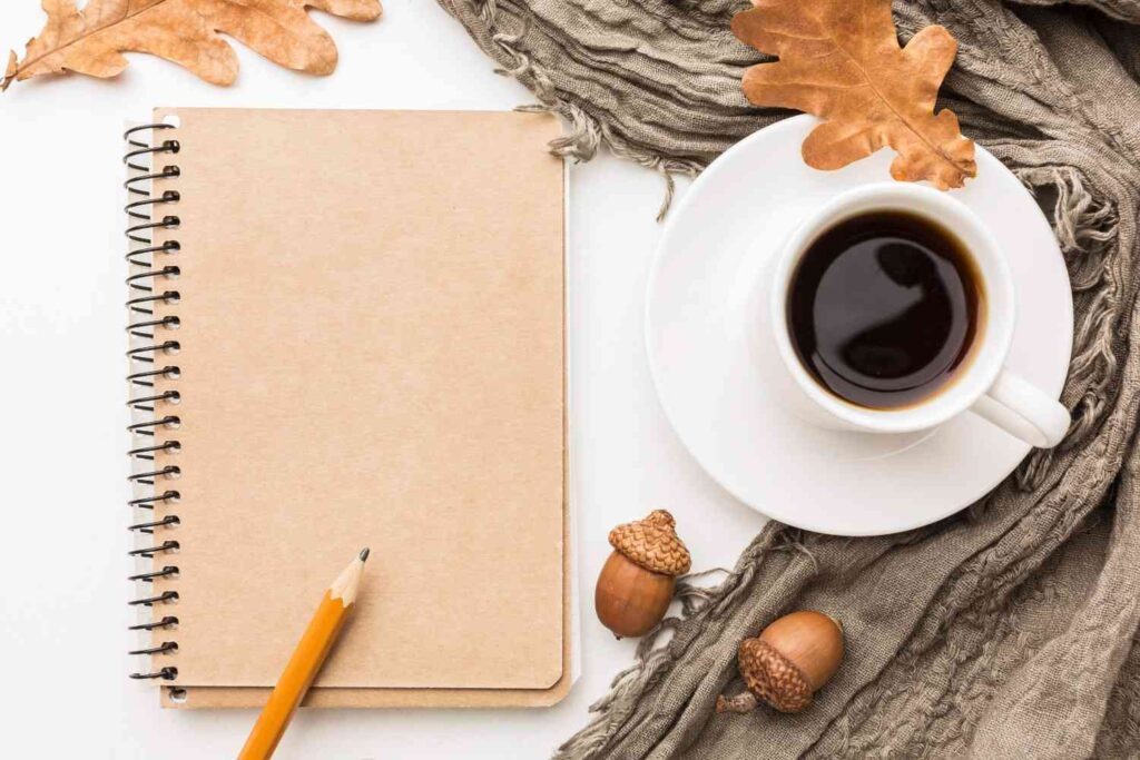 Open journal and coffee cup on a wooden desk for a fall morning journaling routine