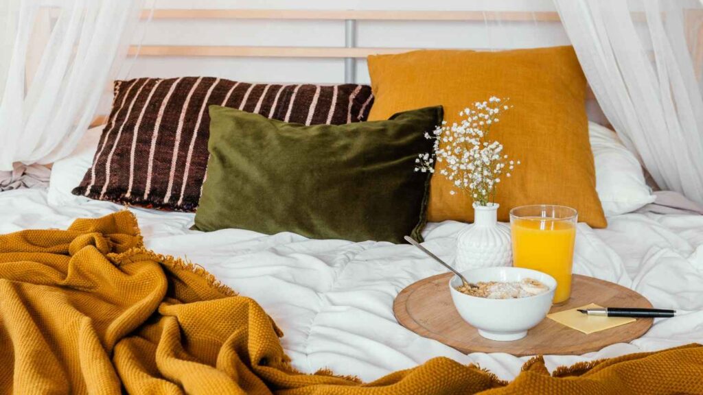 Neatly made cozy autumn bedroom with layered neutral bedding and soft natural light